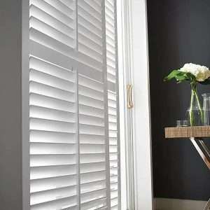 White plantation shutters on window in modern room.