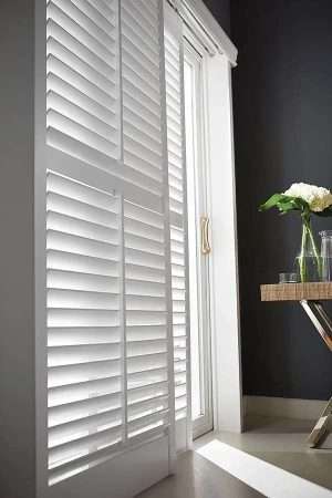 White plantation shutters on window in modern room.